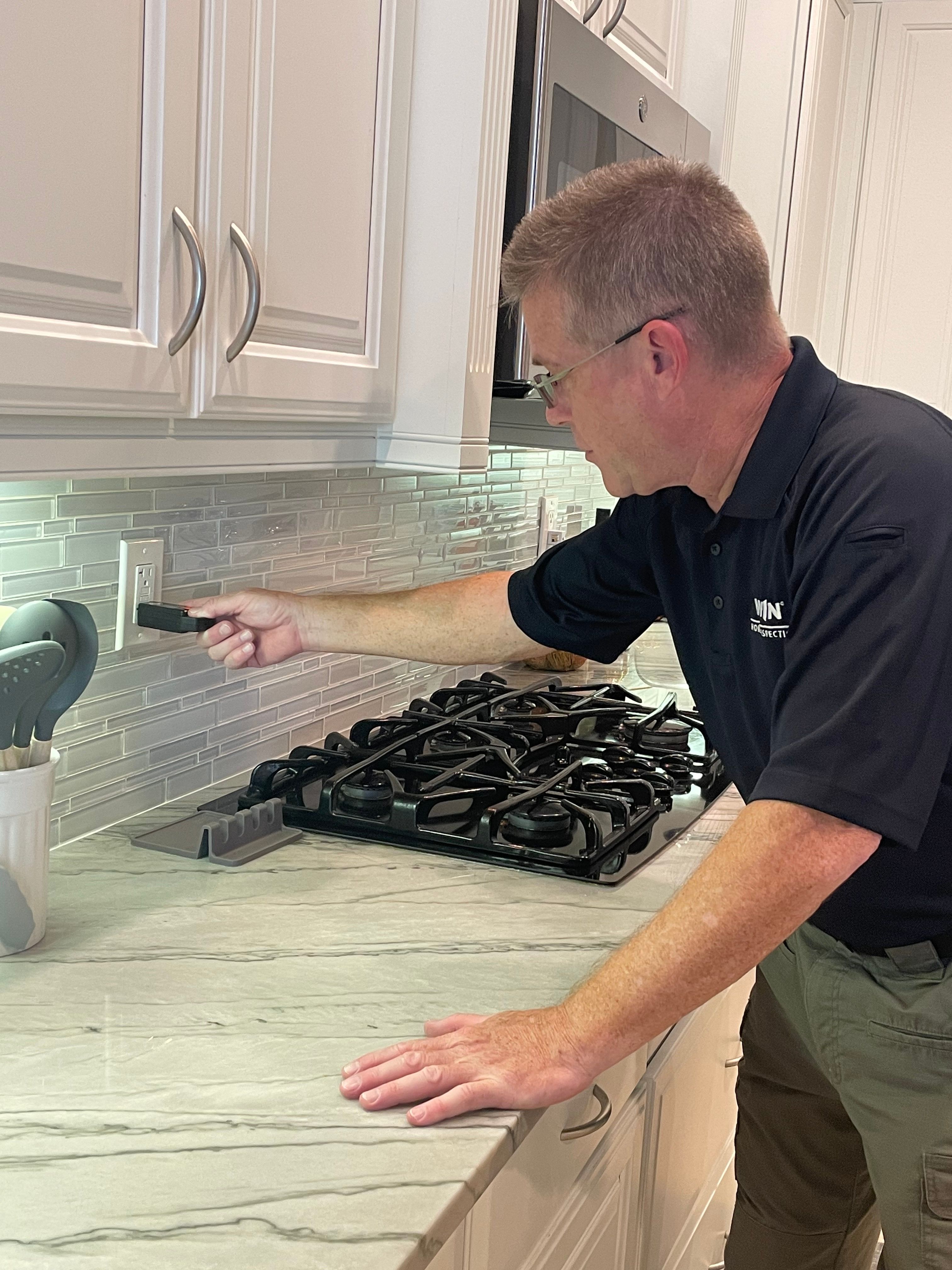 WIN Home Inspector checking an electrical socket in kitchen